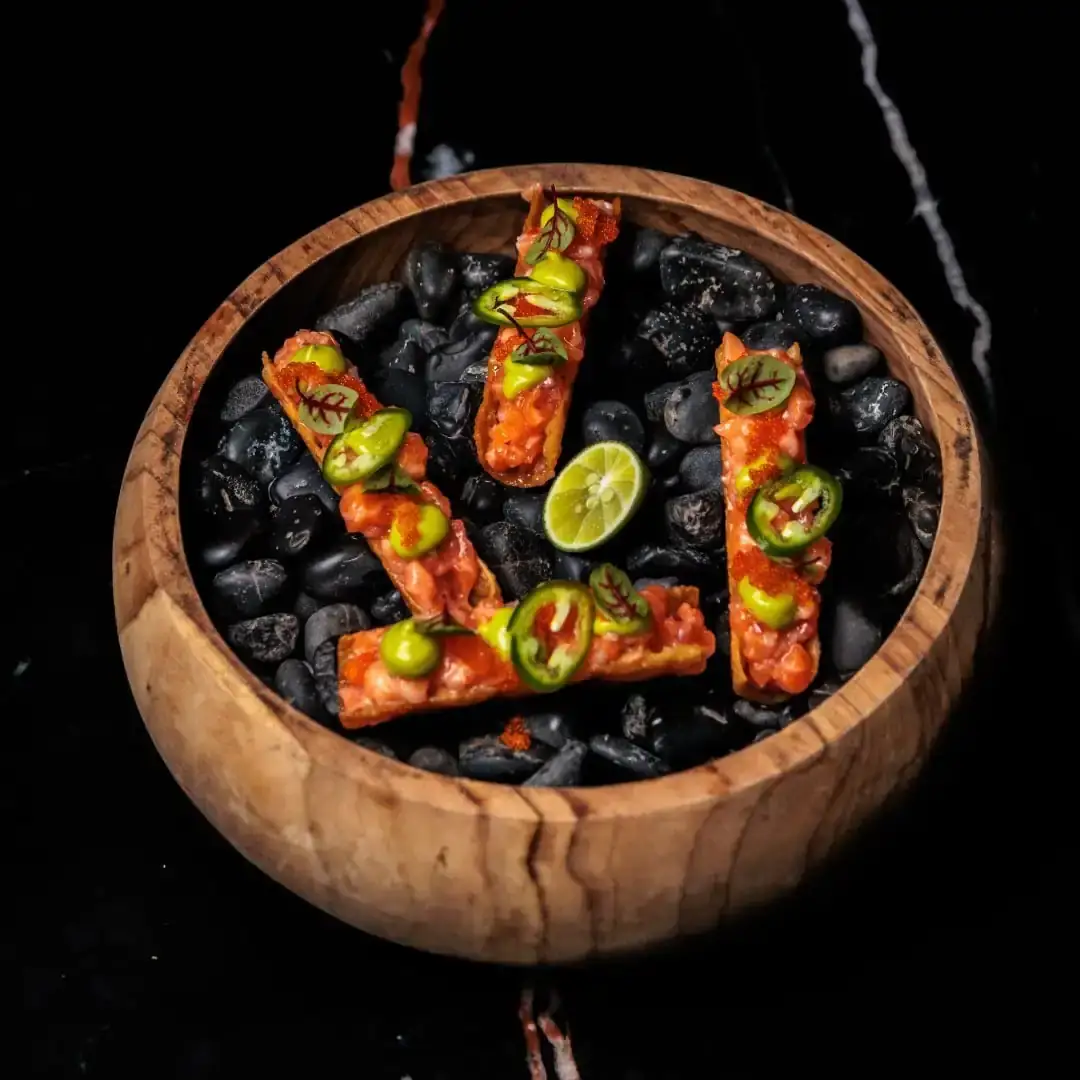 Taquito salmon renyah berdiri di mangkuk batu hitam