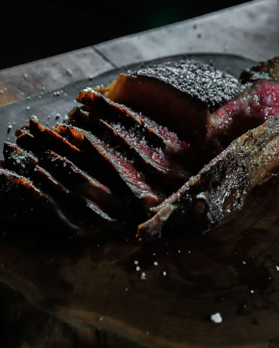 Steak tomahawk gosong, diiris dan dikipas di atas talenan