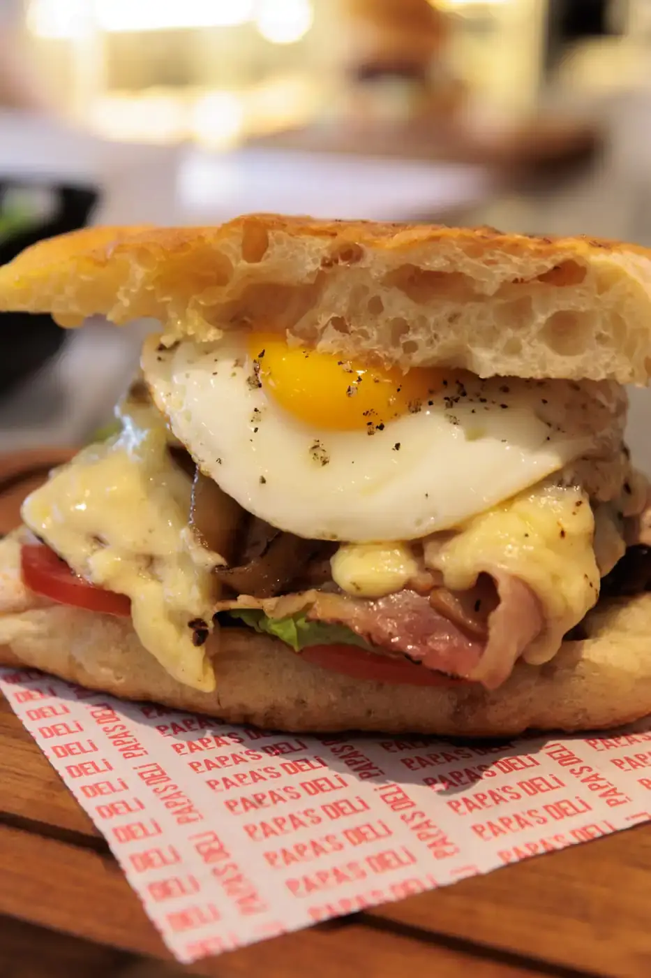 Sandwich sarapan dengan telur setengah matang di atas kertas deli bercetak