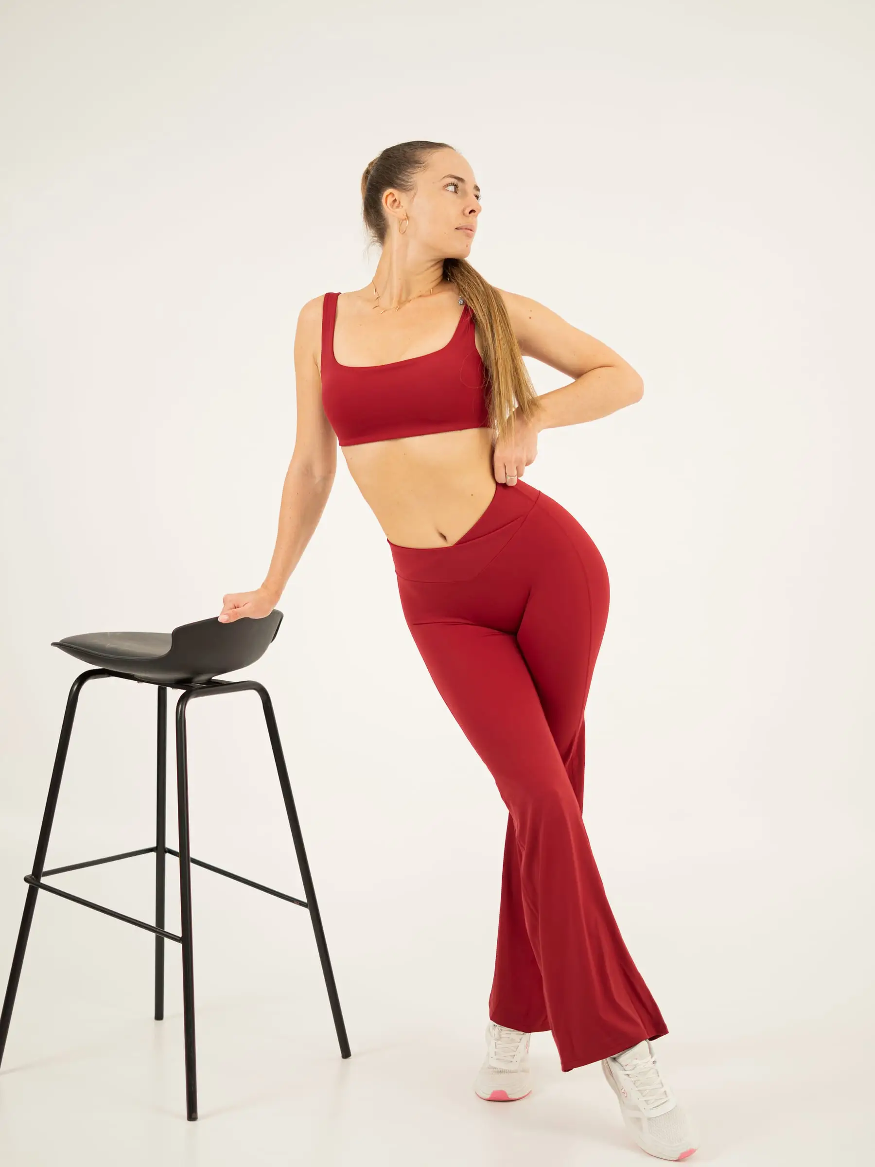 Model activewear merah bersandar di kursi bar