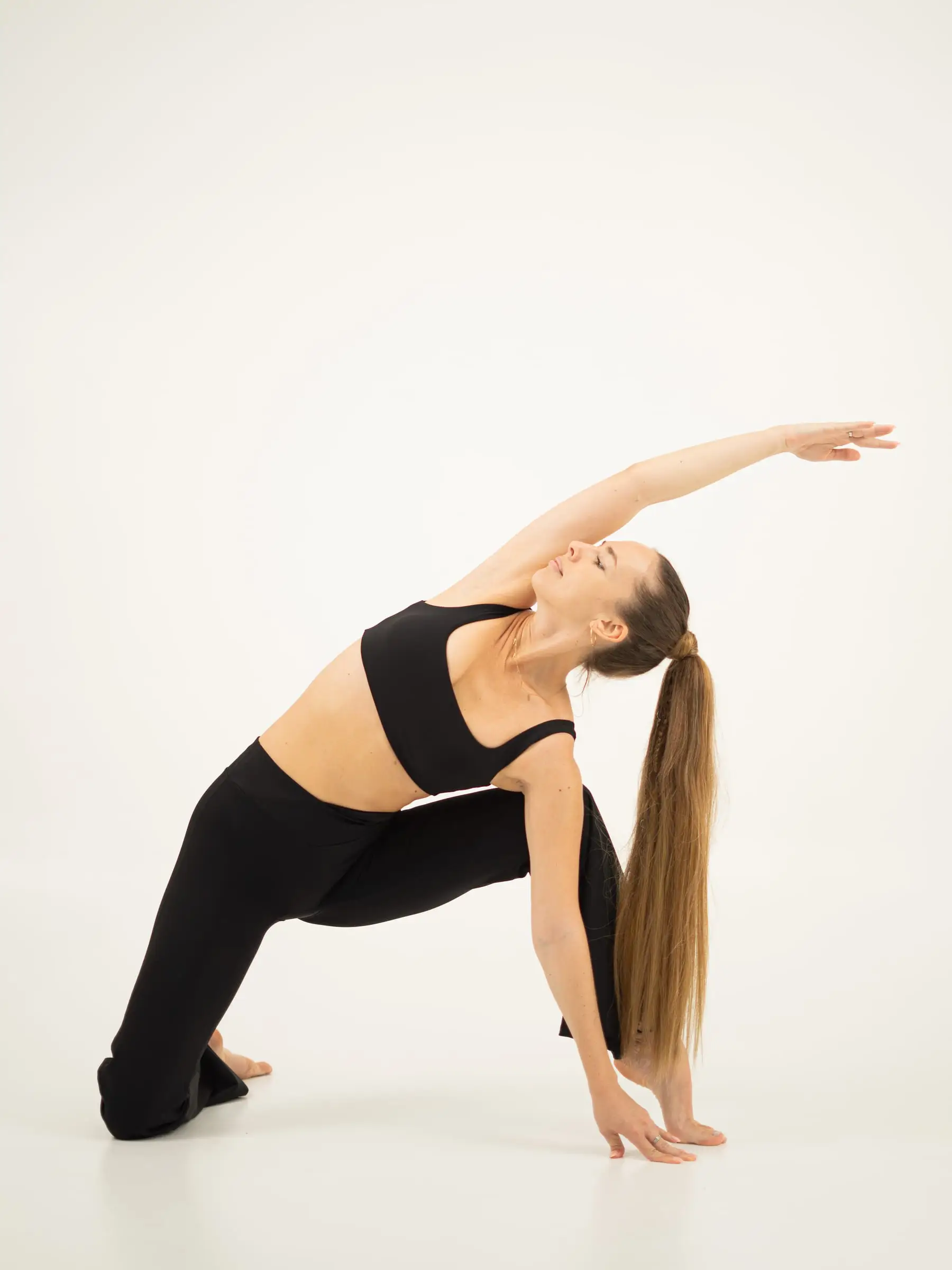 Model activewear hitam dalam pose yoga peregangan samping