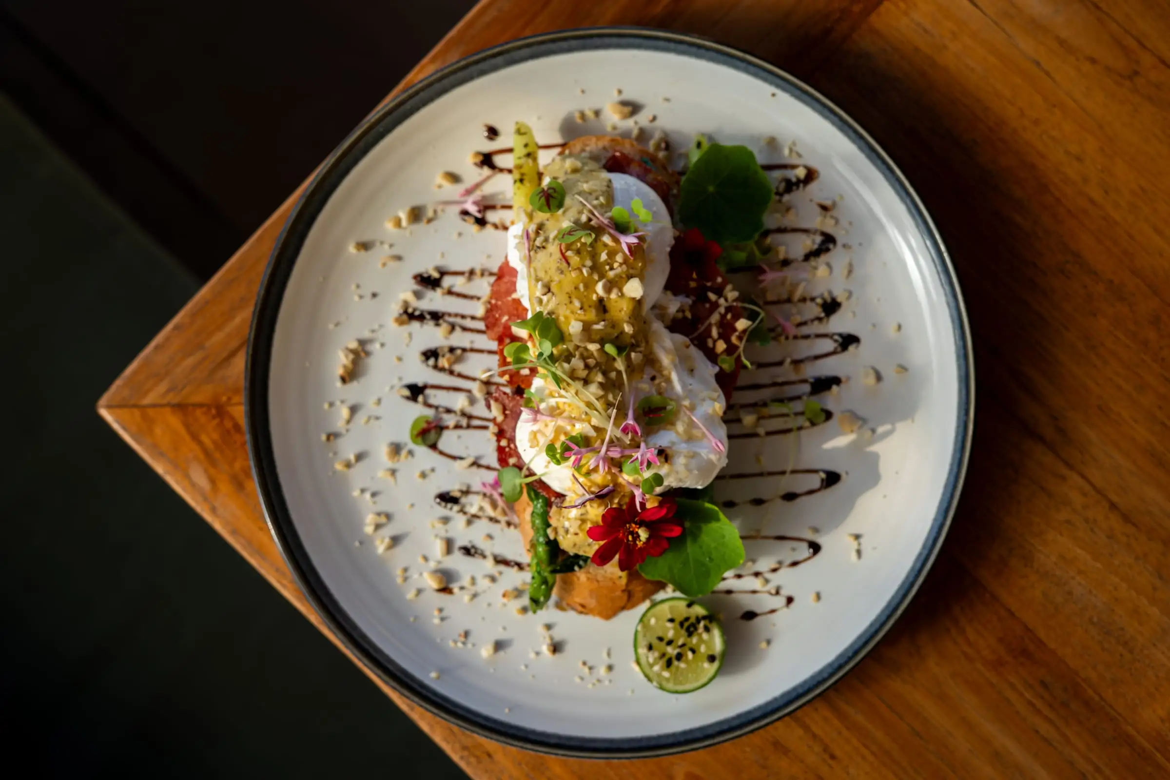 Hidangan brunch berhias bunga di atas meja kayu, difoto dari atas